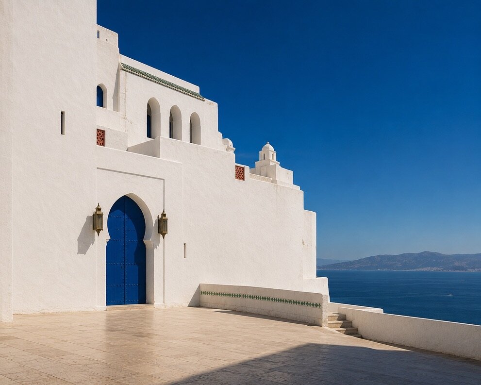 Grande façade blanche de Tanger avec porte bleu cobalt et lanternes dorées, terrasse ouverte sur le détroit et les montagnes au loin