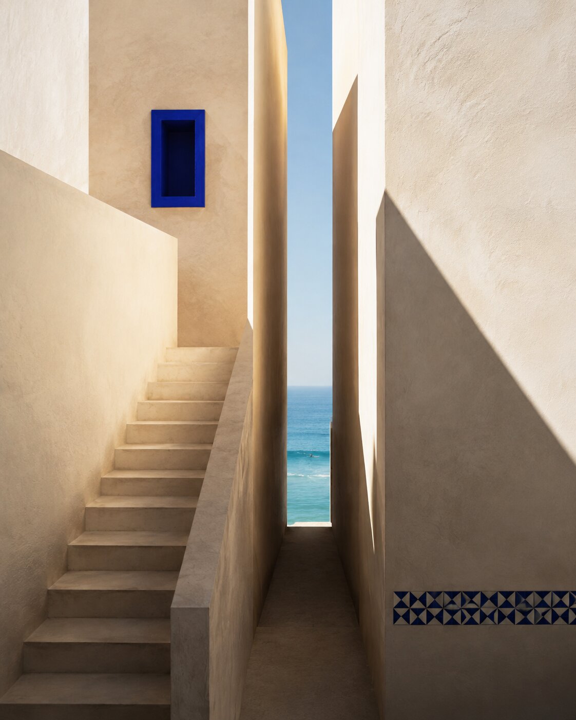 Passage vertical ivoire, escalier asymétrique, niche cobalt et océan aperçu au loin.