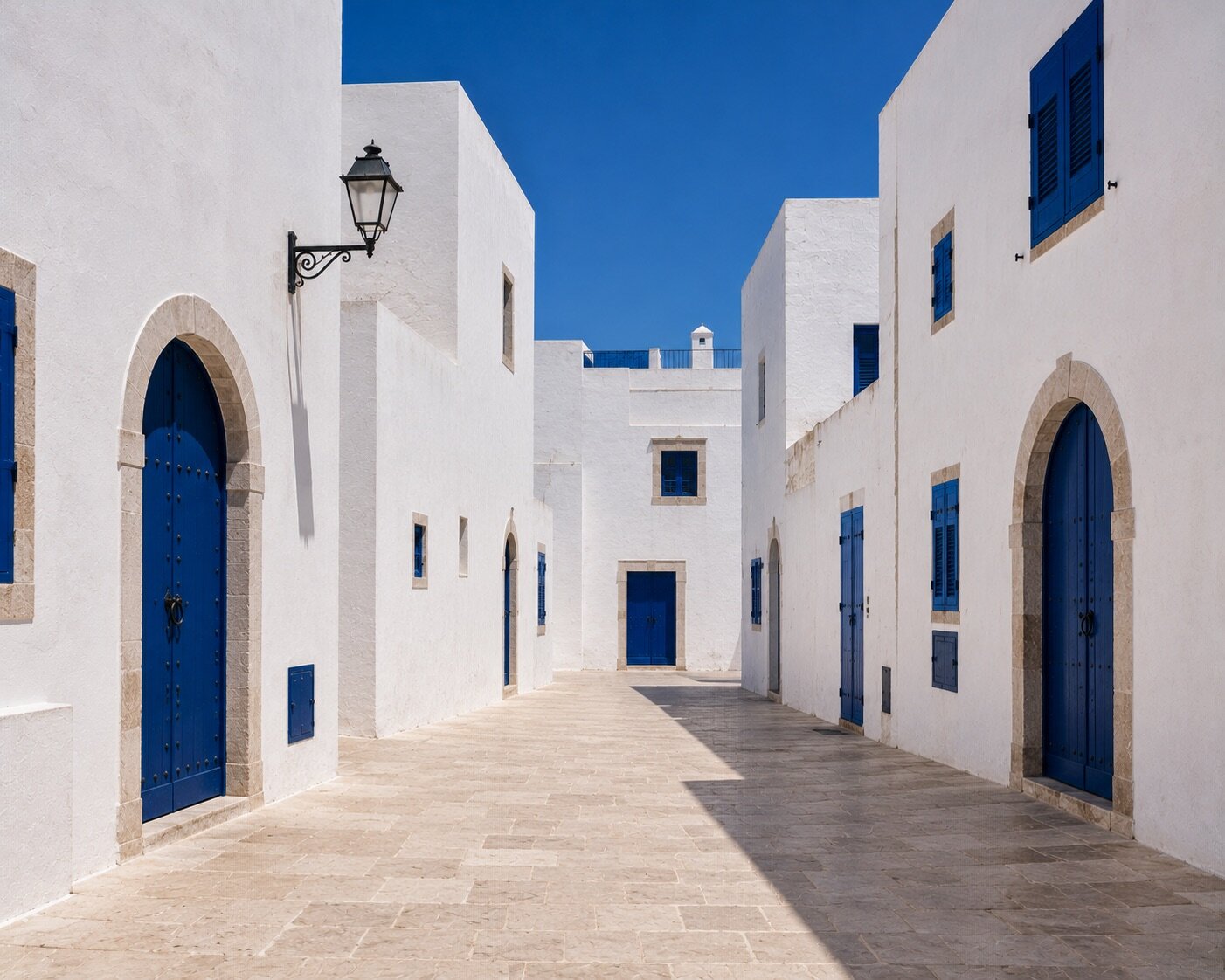 Passage blanc de la médina d'Essaouira ponctué de portes et volets bleu cobalt.