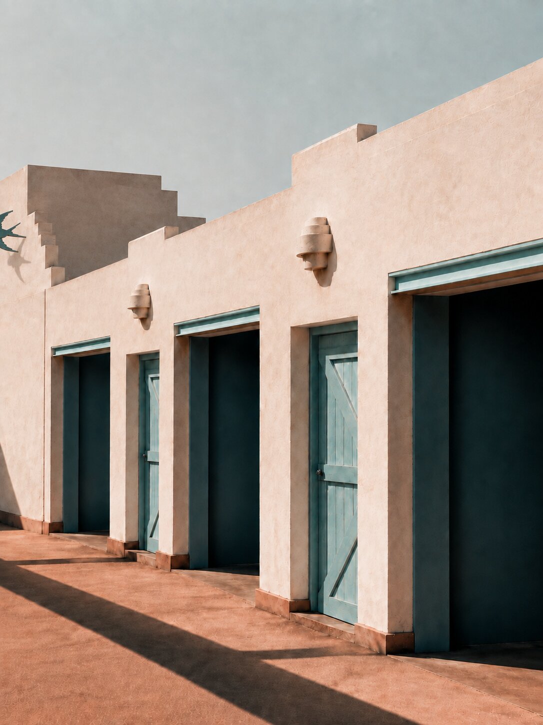 Pale Tucumcari motel façade, turquoise doors and long geometric shadows.