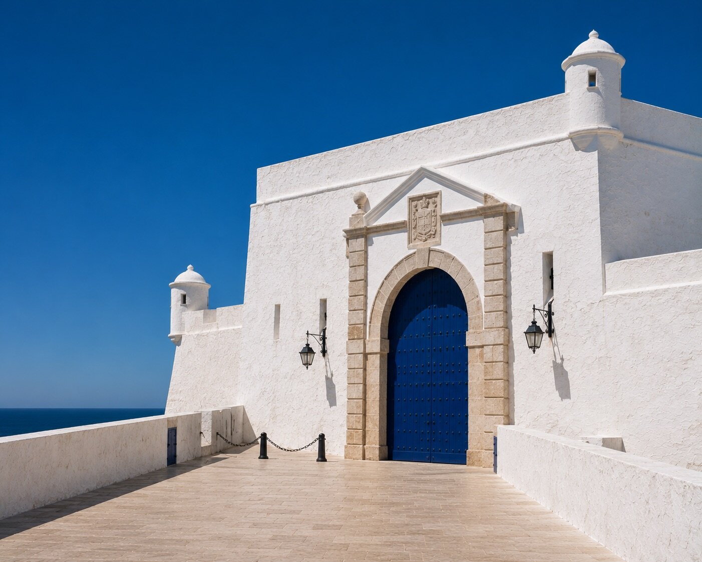 Grande porte bleue monumentale intégrée aux remparts blancs d'Essaouira face à l'Atlantique.