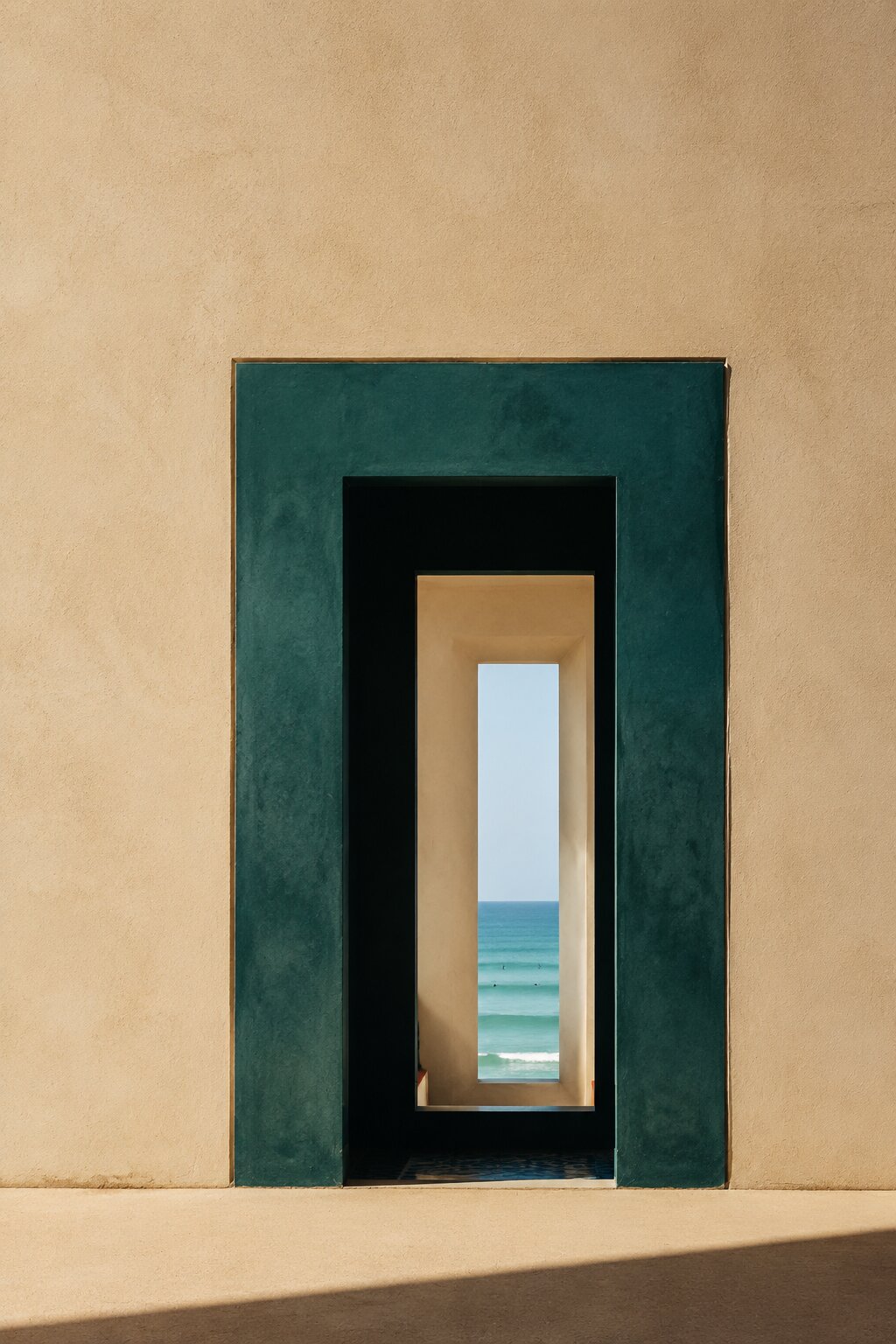 Porte teal profonde, seuil ivoire et horizon atlantique extrêmement fin.