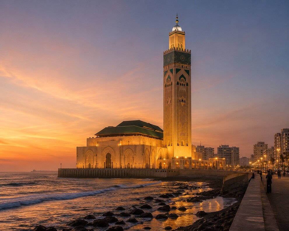 Mosquée Hassan II au coucher du soleil, minaret doré face à l'Atlantique, toits verts et vagues sur les rochers dans la lumière dorée