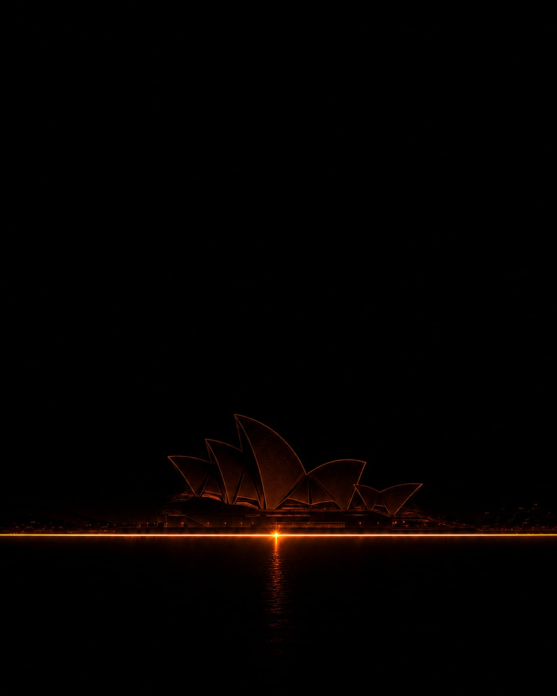 L'Opéra de Sydney faiblement éclairé par une ligne orange réfléchie dans une eau presque noire.